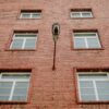 Brick building facade with windows and a lamp.